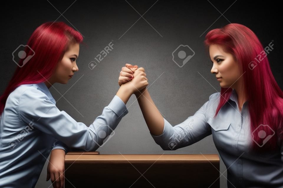 Dwie poważne konkurencyjne kobiety walczące w siłowaniu się na rękę, rywalizują ze sobą.