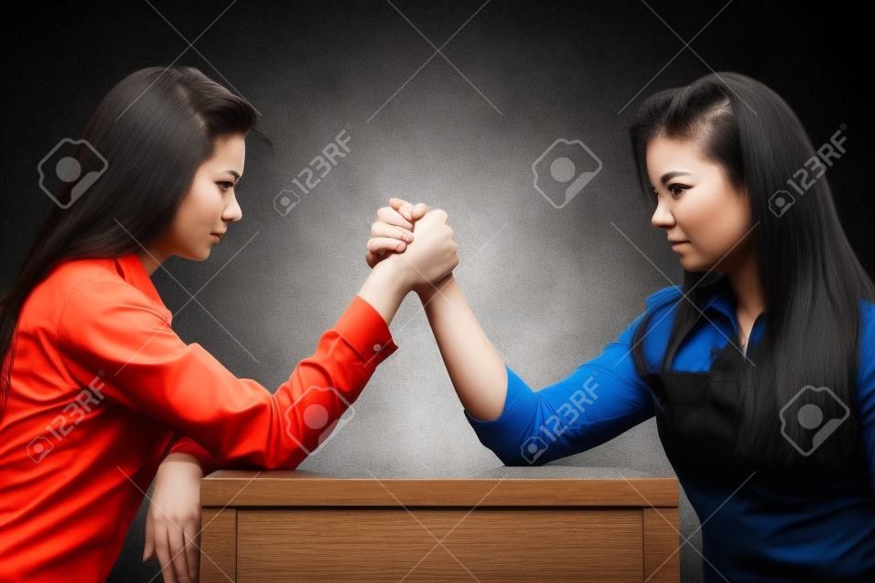 Dwie poważne konkurencyjne kobiety walczące w siłowaniu się na rękę, rywalizują ze sobą.