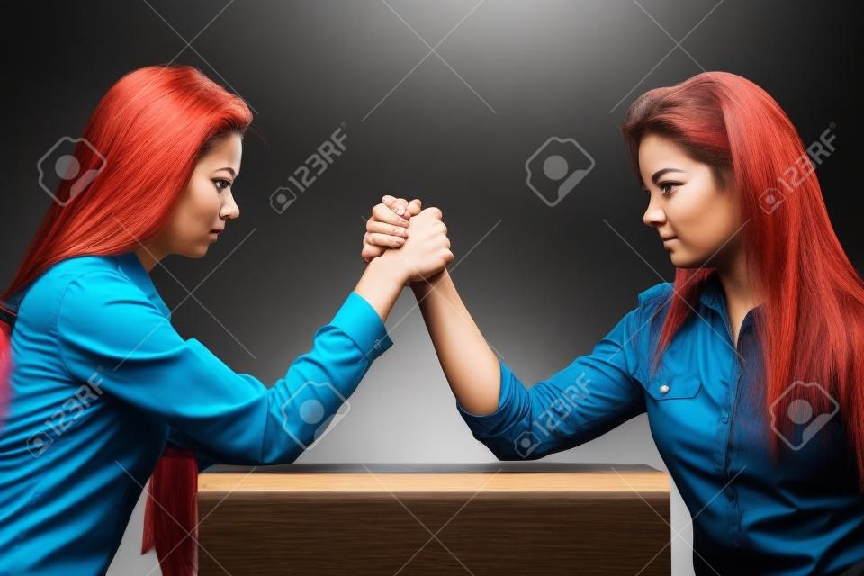 Two serious competetive women having arm wrestling fight, compete with each other.