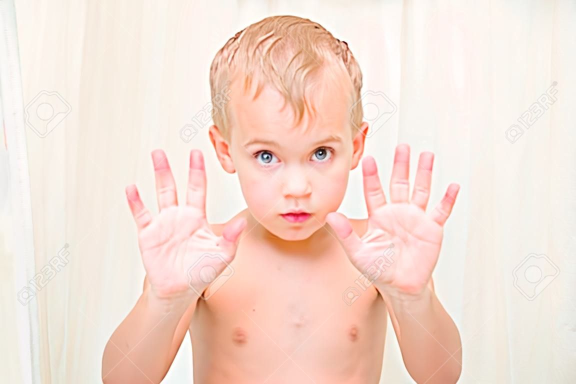 hermoso niño rubio mostrando sus manos en el baño