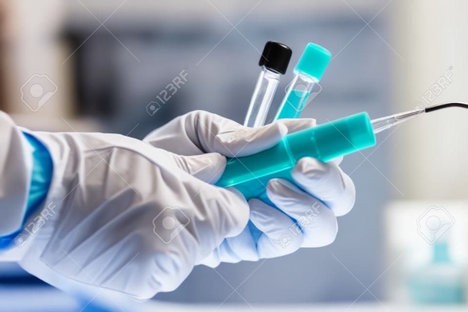 Manos de un médico tomando muestras de tubos de sangre para análisis / técnico de laboratorio extrayendo muestras de sangre con un soporte de tubo en el laboratorio clínico