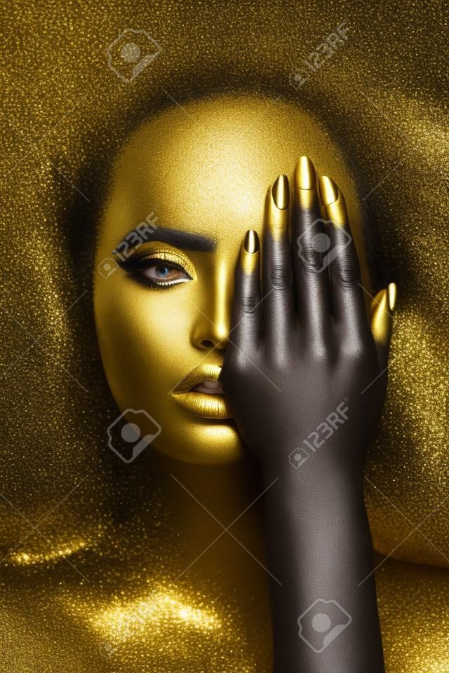 Beauty woman painted in black skin color body art, gold makeup lips eyelids, fingertips nails in gold color paint. professional gold makeup