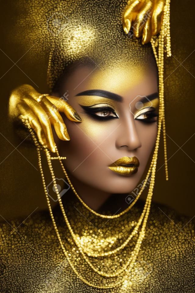 Femme de beauté peinte en art corporel de couleur de peau noire, paupières de lèvres de maquillage d'or, ongles du bout des doigts en peinture de couleur or. maquillage d'or professionnel