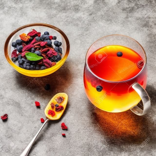 Früchtetee, getrockneten Früchten und Gewürzen, in transparenten Cup auf einem grauen Stein Hintergrund