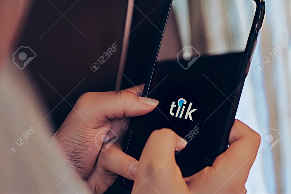 Gdansk, Poland - June 2022: female hand scrolling social media feed on Tik Tok icon app phone. Using social network for entertainment. Frustration time wasting. Addiction Checking News, Friends Activity. Girl Using Mobile Phone, Internet Social Networks Browsing