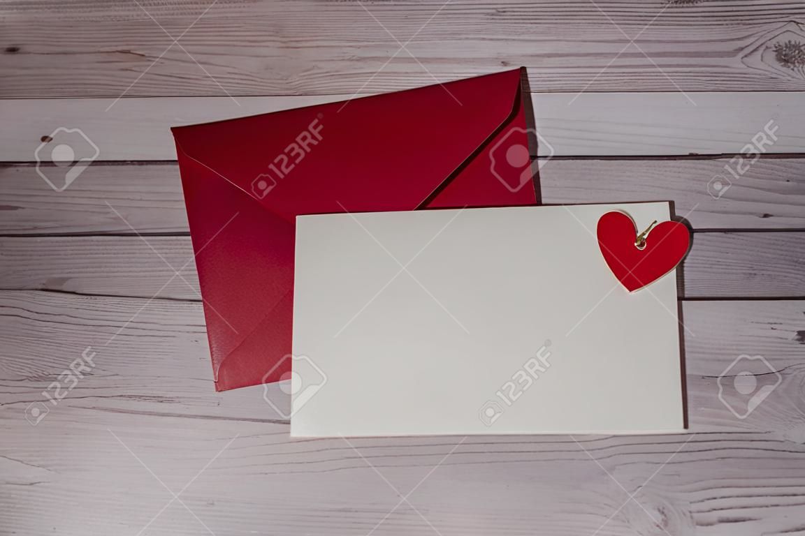 Greeting or invitation card mock up with red envelope on wooden background. Romantic Small hearts Valentine day. Blank paper card copy space for your text. Holiday morning. Top view, flat lay minimalist aesthetic luxury bohemian business branding concept