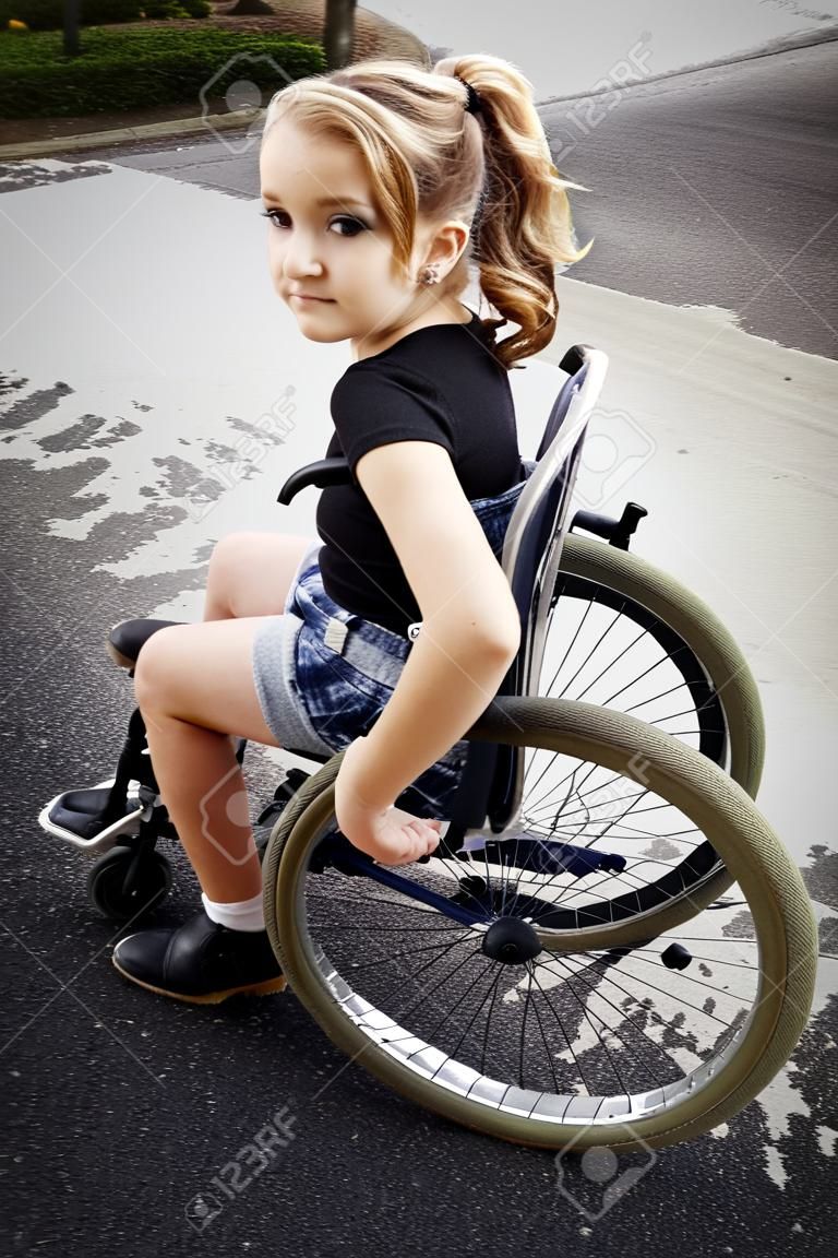 Linda niña con discapacidad que monta una silla de ruedas en el camino
