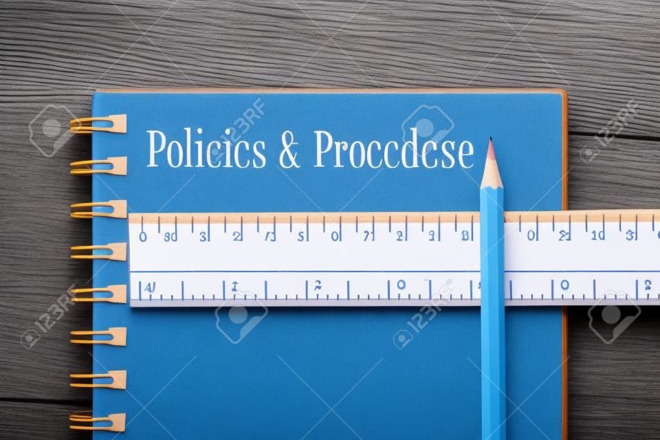 Policies & Procedure word on notebook, wooden ruler and pencil on blue wooden background. Top view.