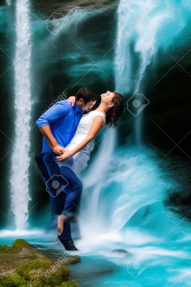Couple hugging and kissing under waterfall
