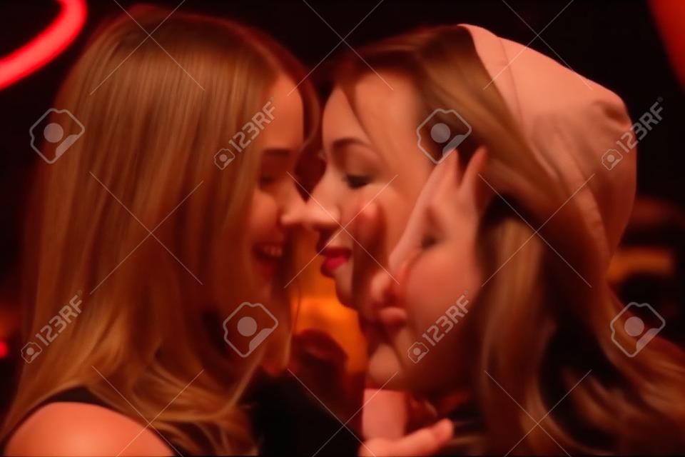 Two girls kisses like lesbians in a night club