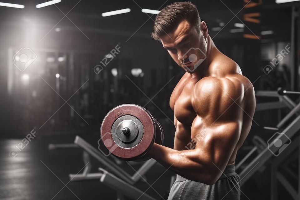 Beau jeune homme caucasien musclé en forme d'apparence de modèle entraînement d'entraînement dans la salle de gym prendre du poids en pompant des muscles, pose, boit de l'eau fitness et concept de nutrition sportive de musculation