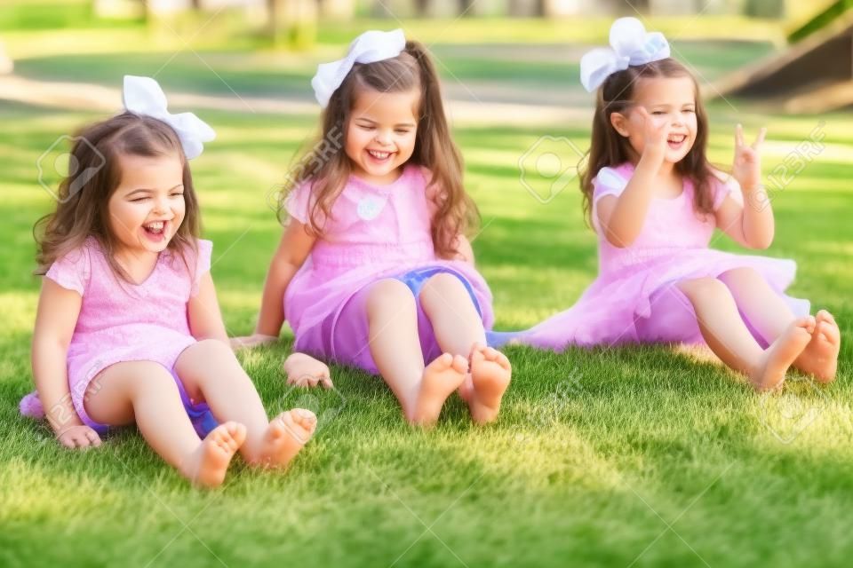 Barefoot little sisters wiggling their toes and having fun at a park