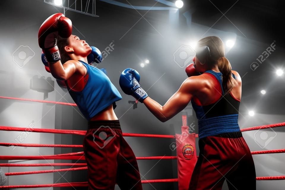 强大的女拳击手在拳击场上打架时用上拳击倒了她的对手