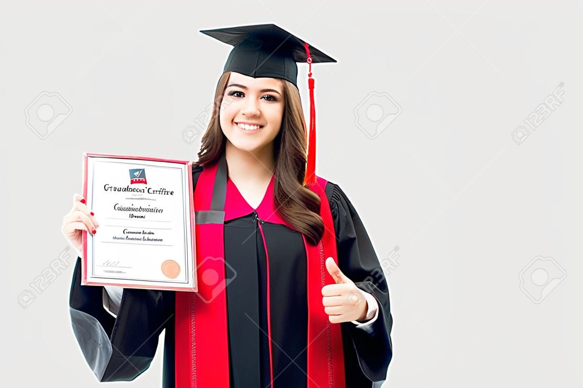 Ritratto di una bella donna in possesso di un certificato di laurea nel suo abito e berretto neri di laurea. Giovane laureato che partecipa alla sua cerimonia di laurea