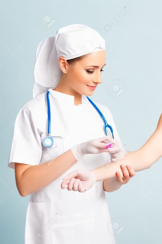 Hermosa enfermera dar una inyección aislada en un fondo blanco