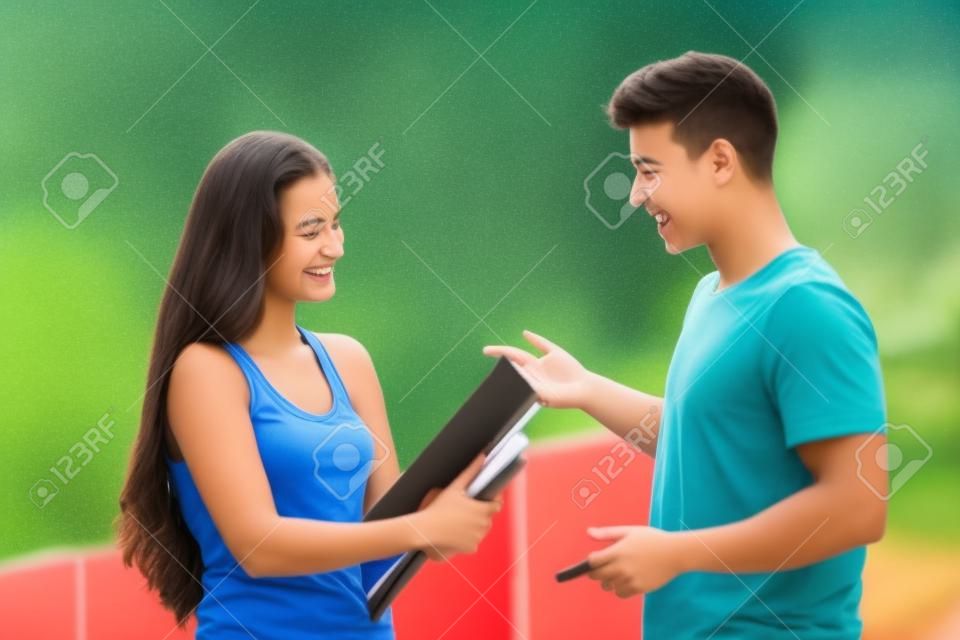 Два студента мальчик и девочка разговаривает счастливы за пределами кампуса