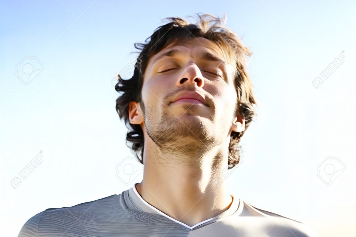 Привлекательный мужчина дышит на открытом воздухе с небо на заднем плане