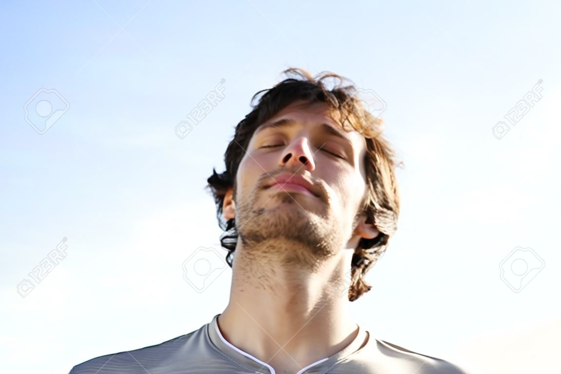 Attractive man breathing outdoor with the sky in the background             