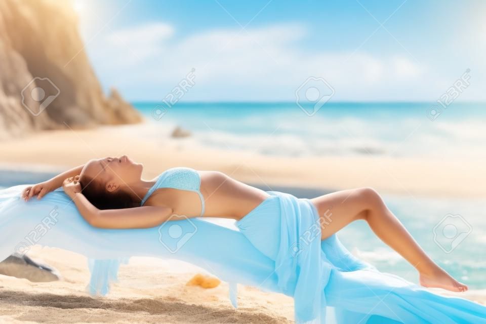 Sunbather belle femme de bronzage sur la plage avec la mer en arrière-plan