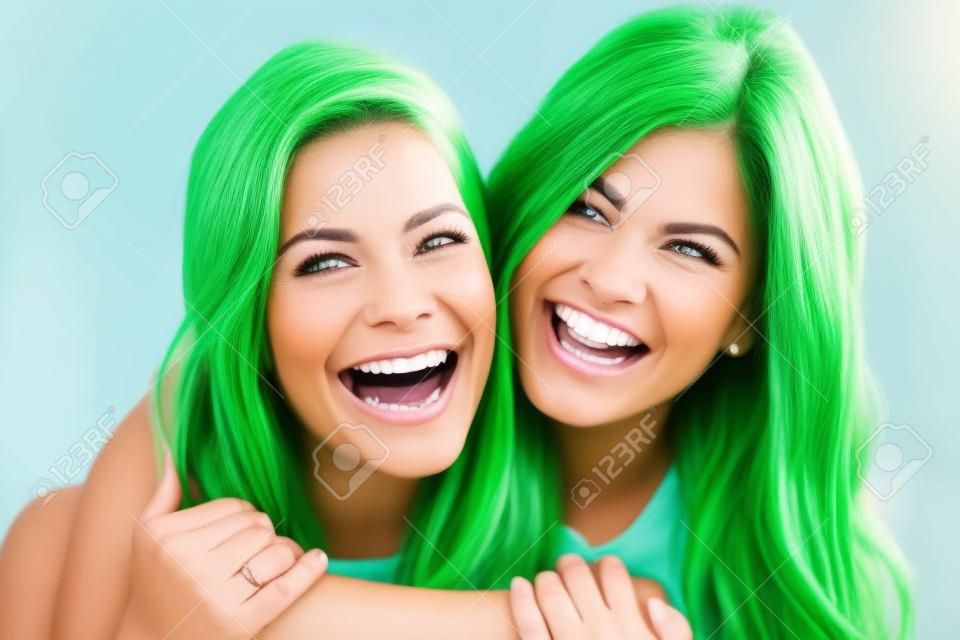 Due amici delle donne ridere con un denti bianchi e perfetti con uno sfondo verde