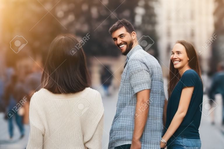Ontrouwe man lopen met zijn vriendin en kijken verbaasd naar een ander verleidelijk meisje