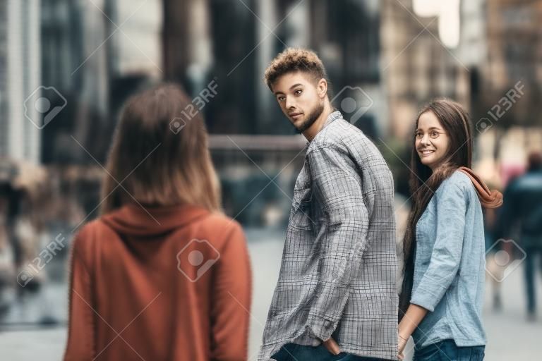 Нелояльных человек, идущий со своей подругой и глядя поражены в другом соблазнительной девушки