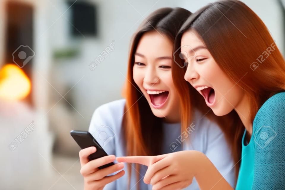 Euphoric Freunde Ansehen von Videos auf einem Smartphone und zeigen auf Bildschirm überrascht