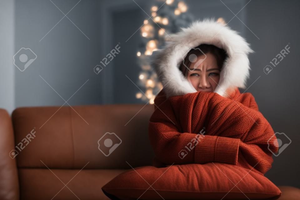 Wściekły kobieta ciepło ubrany w zimnym domu siedzi na kanapie