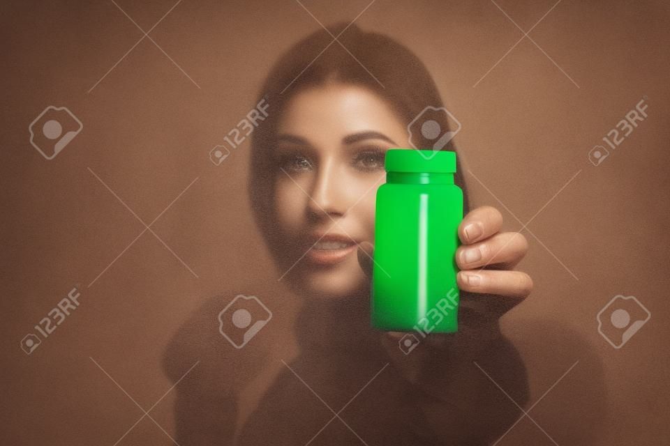 Gros plan d'une femme montrant une bouteille de pilules