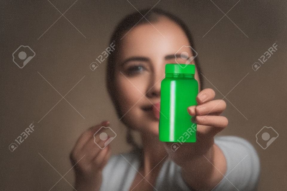 Chiuda in su di una donna che mostra una bottiglia di pillole