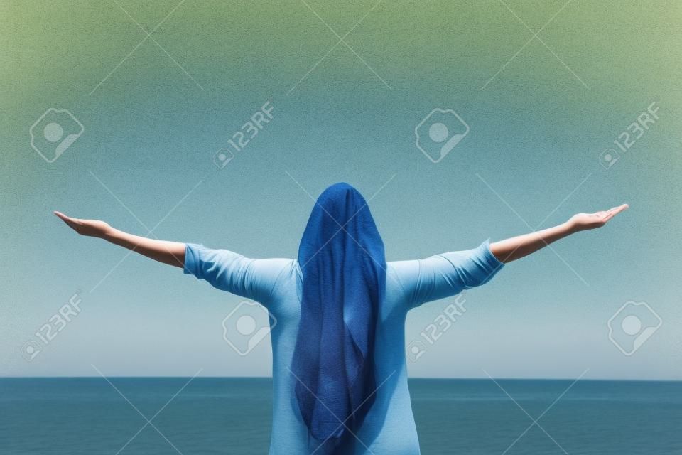 一个女人伸向户外大海和天空的背影