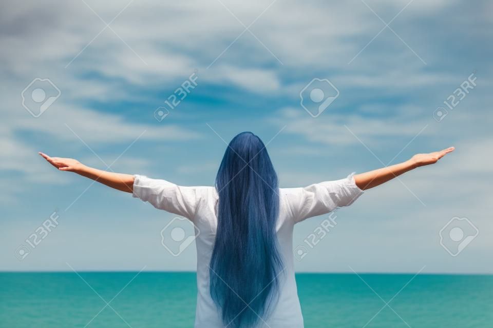 一个女人伸向户外大海和天空的背影