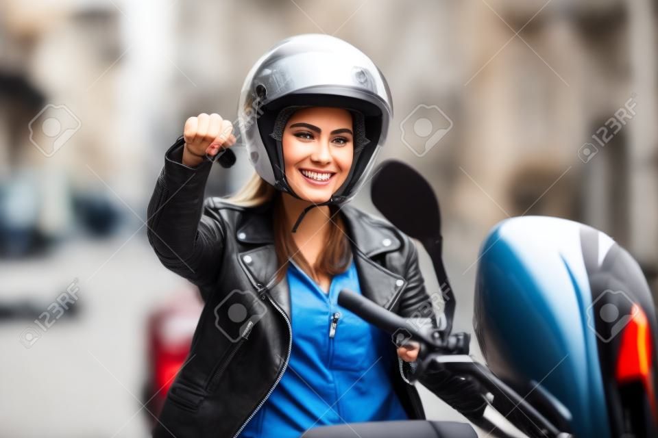 满意的骑自行车的人在街上她的滑板车上显示摩托车钥匙