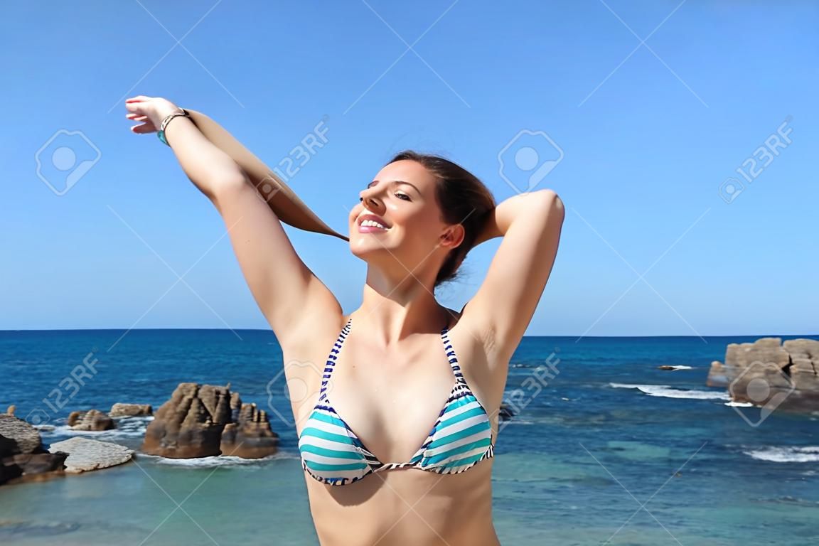 Turista felice che respira aria fresca profonda che mostra le ascelle cerate sulla spiaggia durante le vacanze estive
