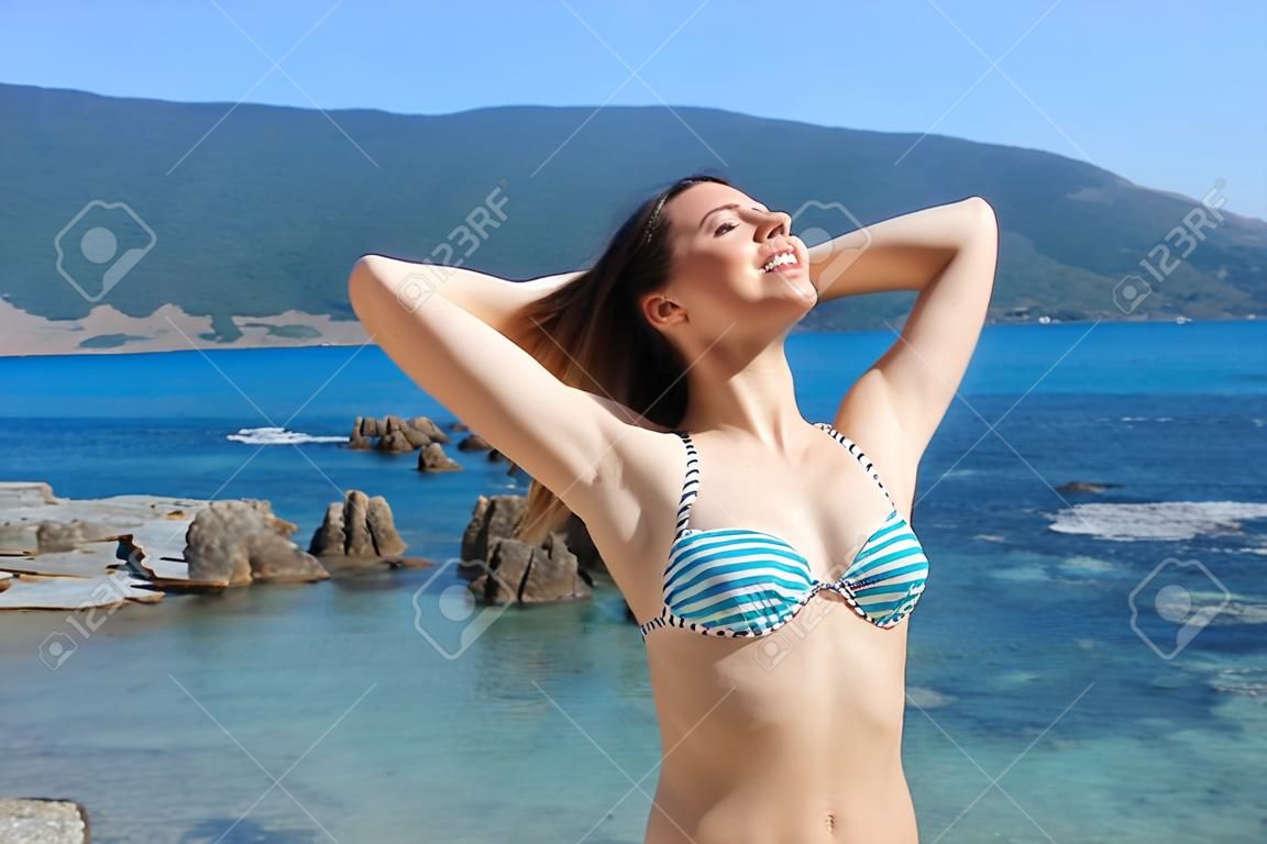 Happy tourist breathing deep fresh air showing waxed armpits on the beach on summer vacation