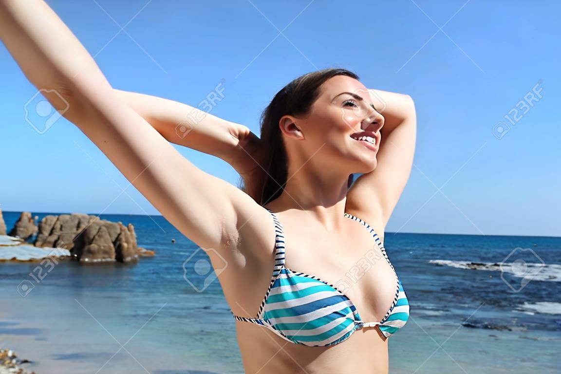 Happy tourist breathing deep fresh air showing waxed armpits on the beach on summer vacation