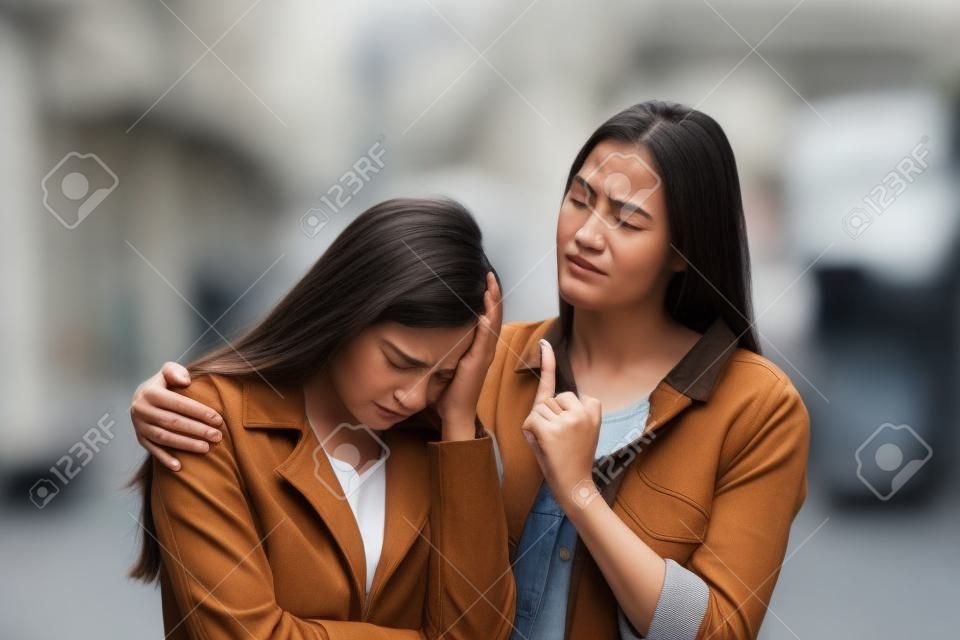 Sad woman being comforted by a bad friend in the street