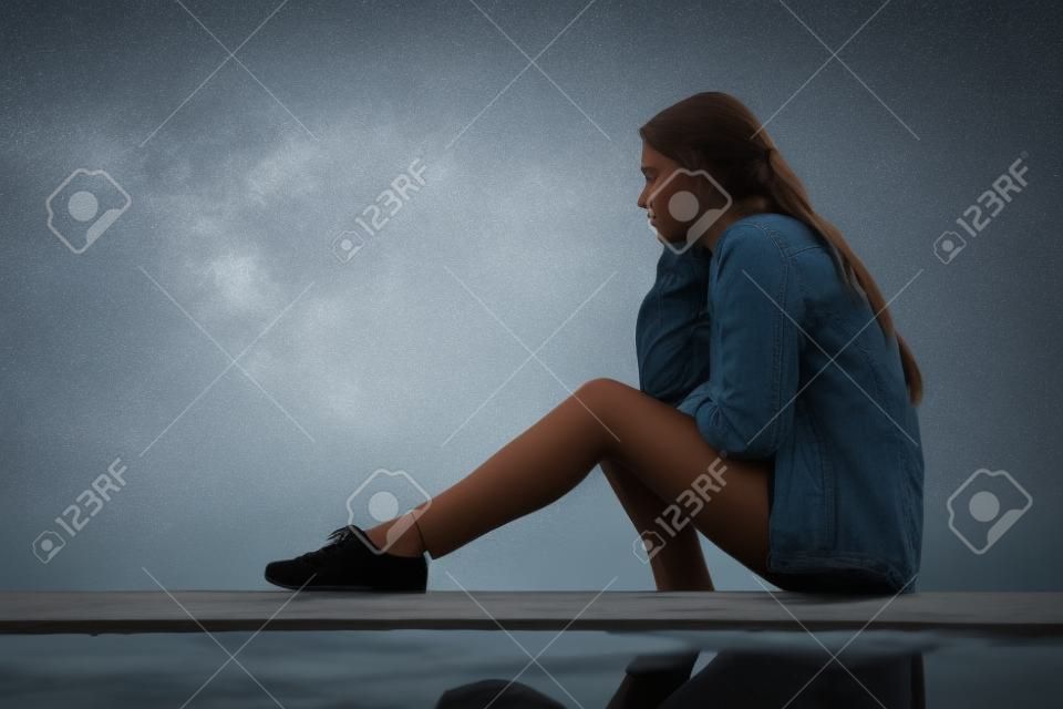 Seitenansicht Porträt eines traurigen Mädchens, das allein wegschaut und draußen sitzt und den Horizont betrachtet