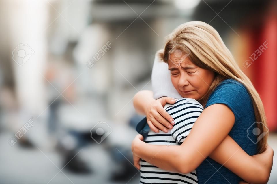 Bedauernde Frau, die einen Freund umarmt, der sich auf der Straße versöhnt