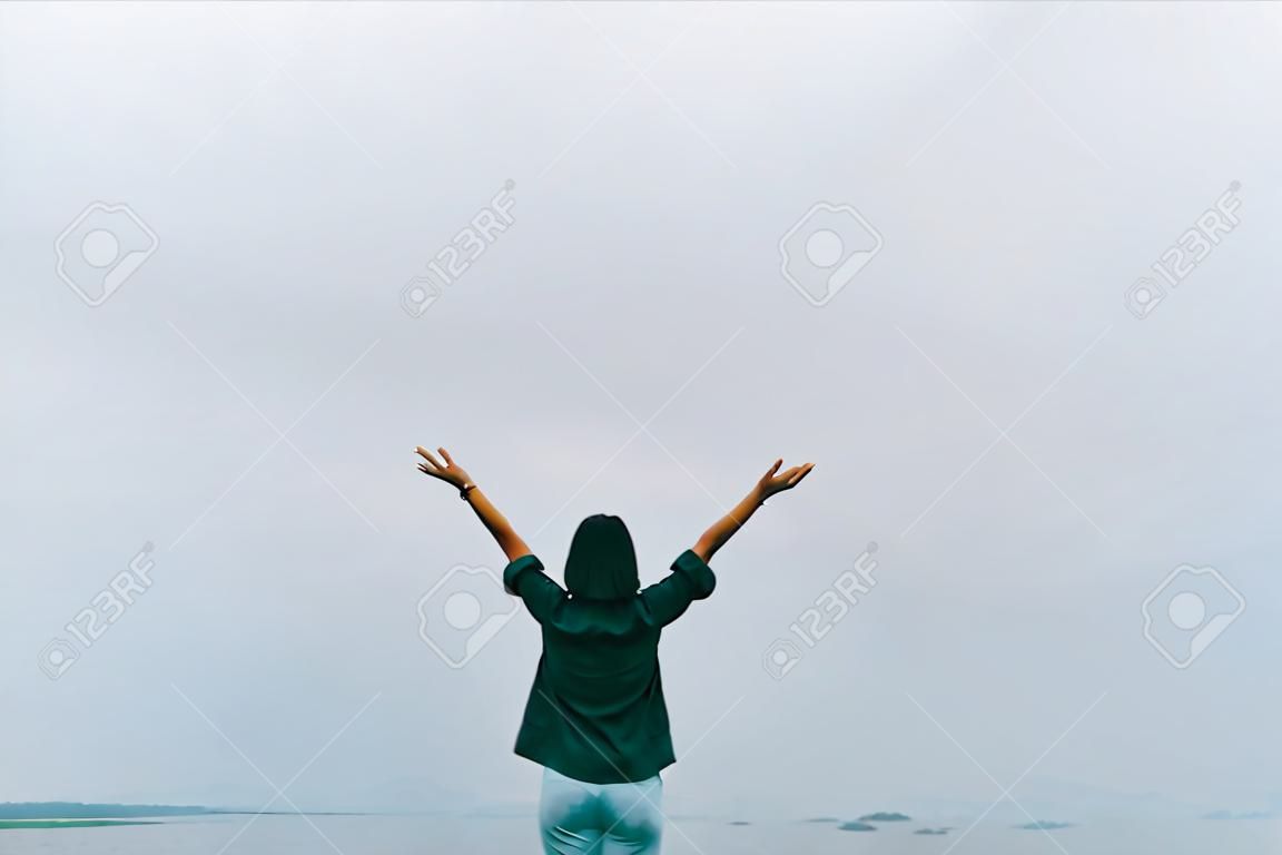 Woman rise hands up to sky freedom concept with blue sky and summer field background.