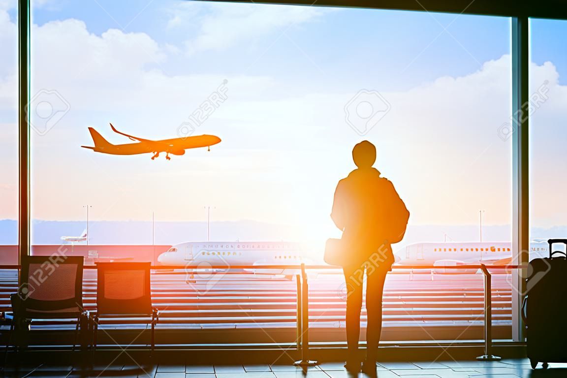 Viaggiatore felice che aspetta il volo in aeroporto, terminale di partenza, concetto di immigrazione