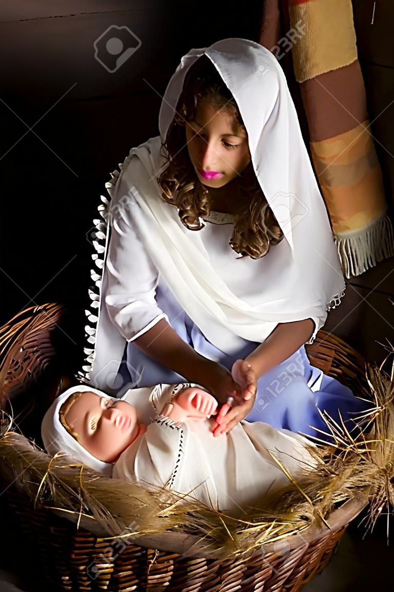 Подросток девочка, играя роль Девы Марии с куклой в прямом эфире Рождественские сцены Рождества