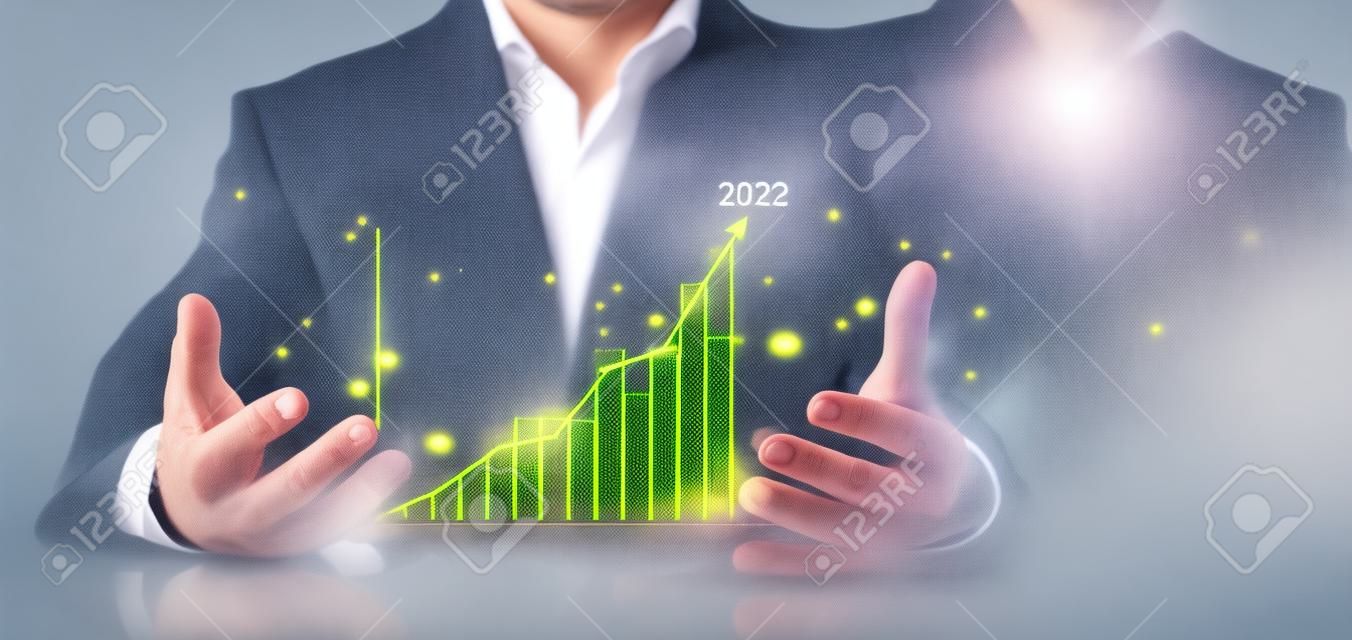 O homem de negócios mostra o gráfico dourado da barra do mercado de ações cresce até o alvo. Conceito do financiamento do negócio. Mãos do homem de negócios Mostra o gráfico do sucesso, estoques cresce cada ano e estabelece metas para 2023