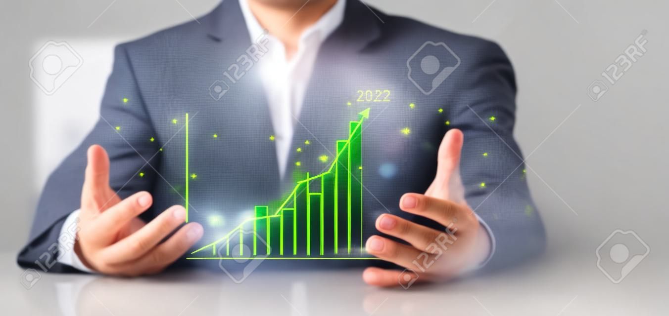 Businessman show golden stock market bar chart grow up to target. Business finance concept. Businessman's hands Show success graph, stocks grow every year and set goals for 2023