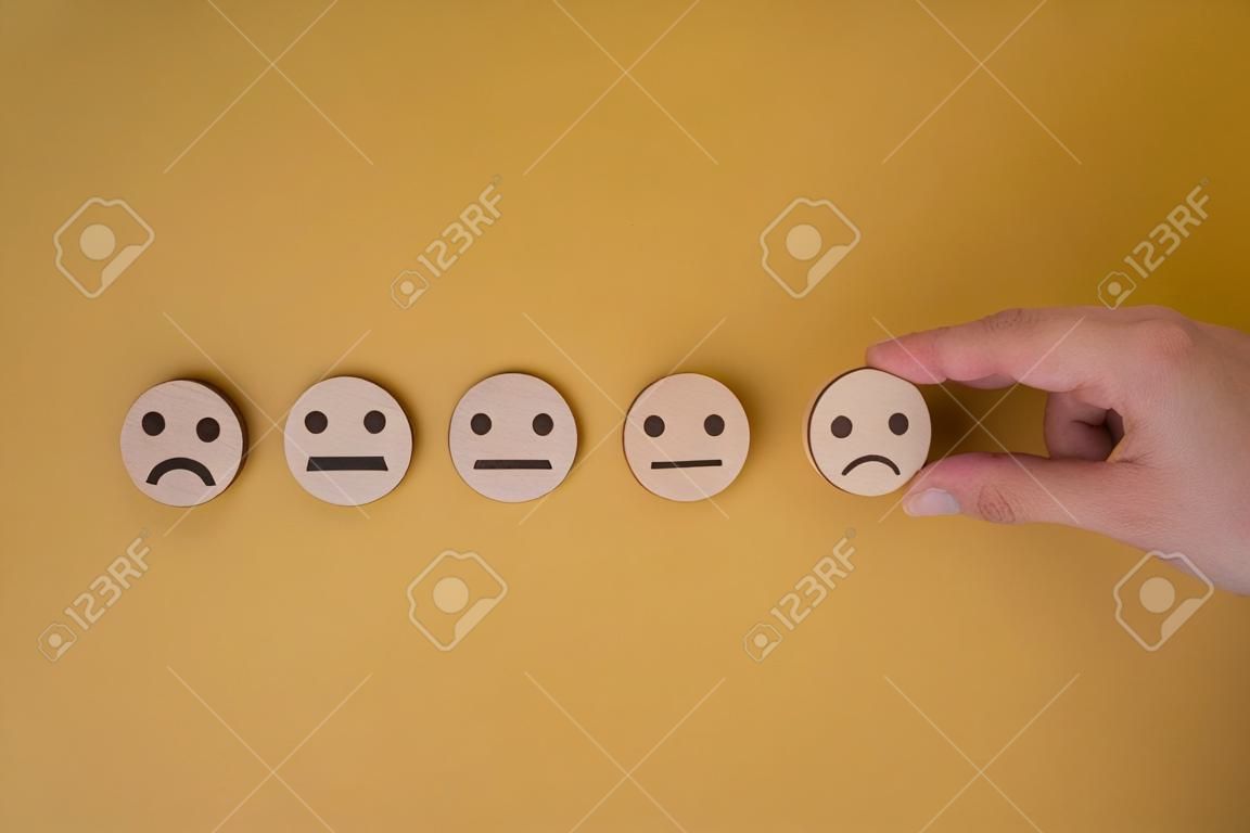 Hand wood block circle chooses icon smile face Customer service evaluation and satisfaction survey concepts on yellow background. copy space
