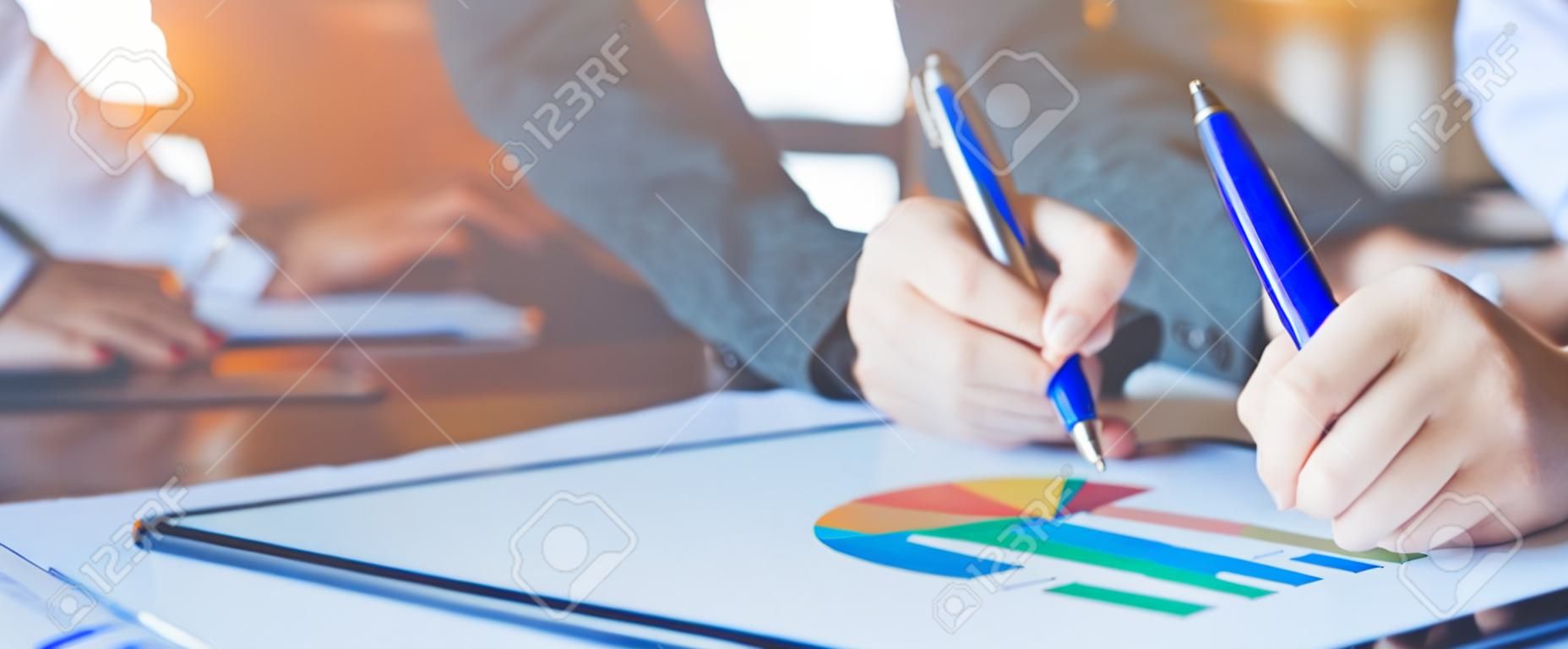Mano de mujer de negocios escribiendo en tablas y gráficos que muestran resultados.Banner web.