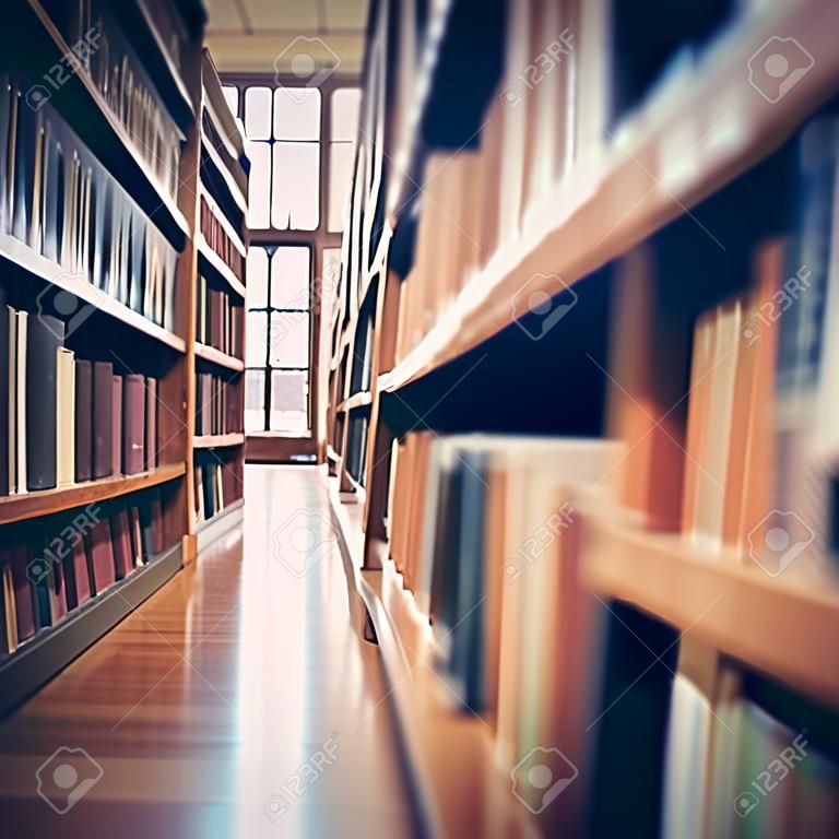 Blurred public library interior space. Defocused bookshelves with books - vintage tone. Learning and education concept background