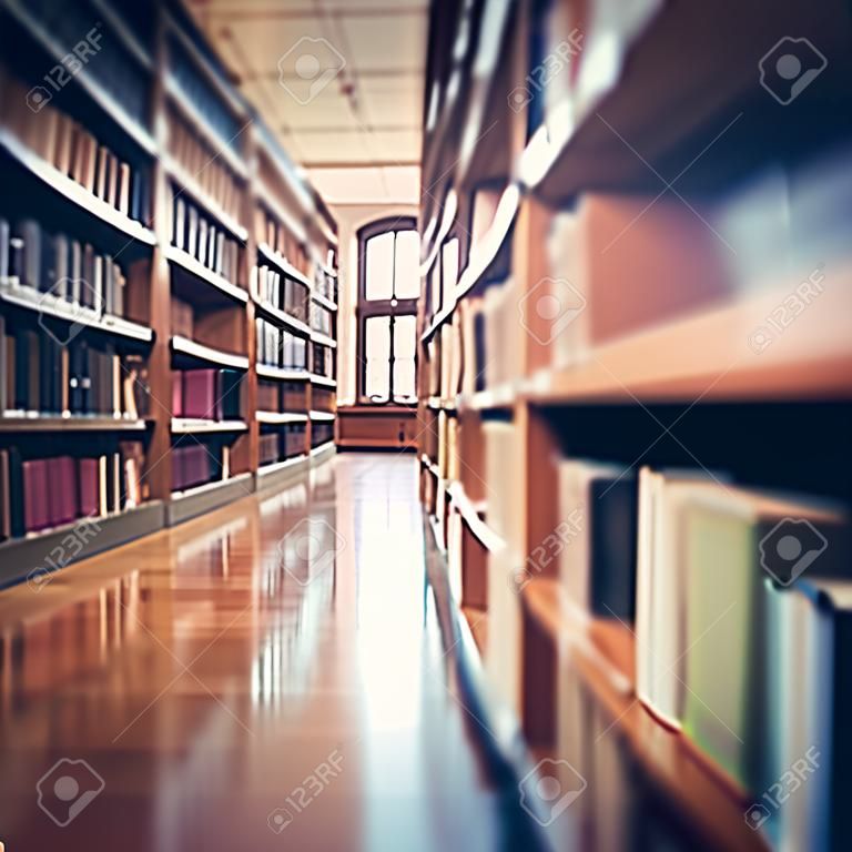 Blurred public library interior space. Defocused bookshelves with books - vintage tone. Learning and education concept background