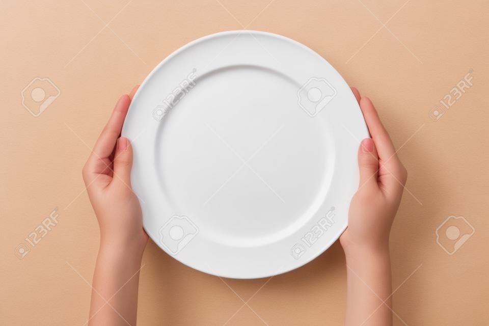 Femme (femme) deux mains tiennent (soutien) un plat blanc (plaque) isolé vue blanc et top.