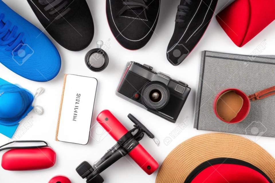 Concepto de viaje con pasaporte, sombrero, zapatillas, taza, cámara y libros sobre el fondo blanco.
